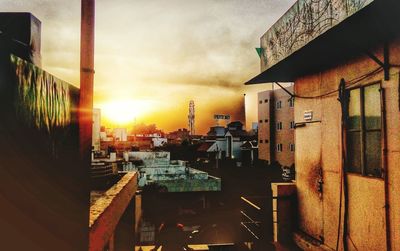 Houses in city against sky at sunset