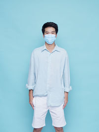 Portrait of young man standing against blue background