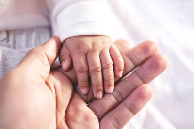 Baby holding mothers hand at home