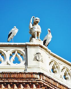 Low angle view of seagull perching on sculpture against sky