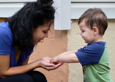 Cute little toddler is playing pebbles with mom on the back porch