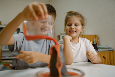 Children, boy and girl are conducting an experiment with volcanic eruption at home