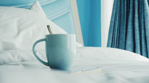 Close-up of coffee cup on bed