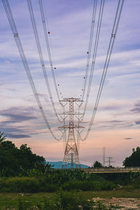 Low angle view of electricity pylon against sky during sunset