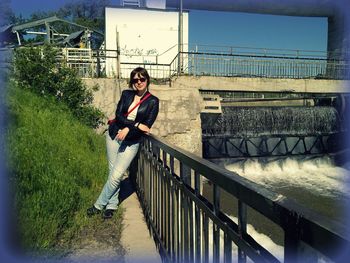 Full length of young man sitting on footbridge