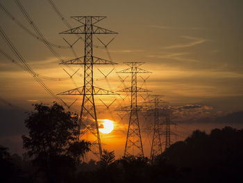 Low angle view of silhouette electricity pylon against sky during sunset