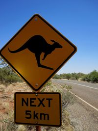 Information sign on road against clear blue sky