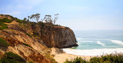 Scenic view of cliff by sea against sky