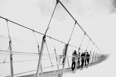 Men on power lines against sky