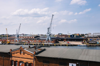 High angle view of cranes on buildings against cloudy sky