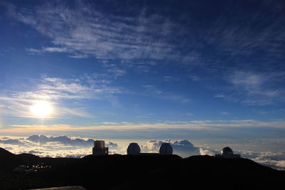 Silhouette buildings in town against sky during sunset