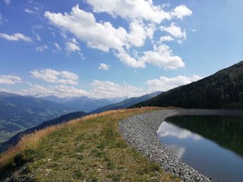 Scenic view of lake by mountains against sky