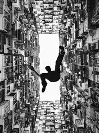 Directly below shot of man jumping against buildings
