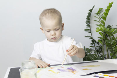 A small child draws a drawing with watercolors, develops and learns.