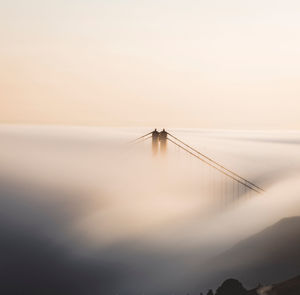 Bridge amidst fog during sunset 