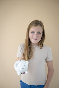 Portrait of young woman with piggy bank against white background