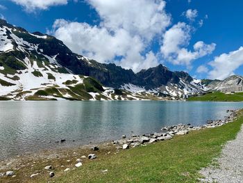 Scenic view of lake by snowcapped mountains against sky