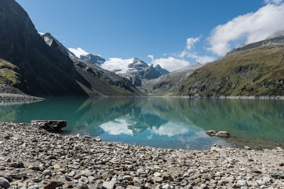 Scenic view of lake by snowcapped mountains against sky