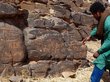 Side view of male guide showing tribal art on rocks