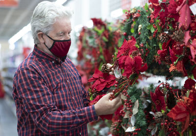 Man with mask holding red decorations in store