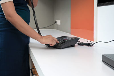 Midsection of man using mobile phone on table