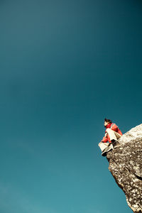 Low angle view of man against clear blue sky