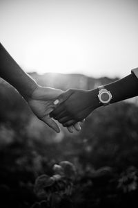 Close-up of hands against sky