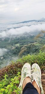 Low section of person on mountain against sky