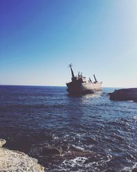 Abandoned ship in sea against clear blue sky