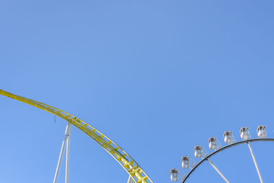 Low angle view of rollercoaster against clear blue sky