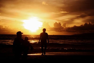 Silhouette people at beach against sky during sunset