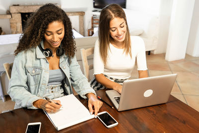 Young woman using phone on table