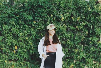 Portrait of young woman standing against plants