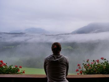 Rear view of man standing on mountain against sky