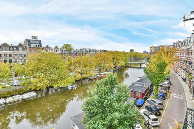 High angle view of river amidst trees and buildings against sky