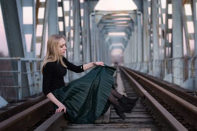 Woman sitting on railroad track