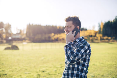 Mid adult male farmer talking on mobile phone on field