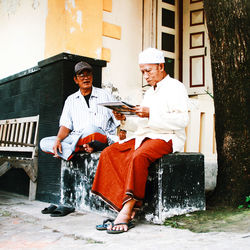 Man sitting with umbrella in front of building