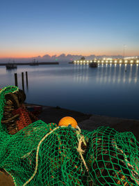 Fishing net at harbor against sky during sunset