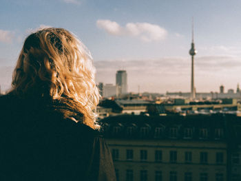 Rear view of woman standing in front of fernsehturm tower