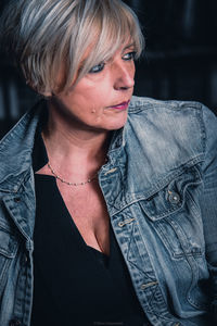 Mature woman in denim jacket looking away