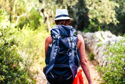 Rear view of backpack female hiker walking in forest