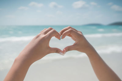 Midsection of man holding heart shape against sky