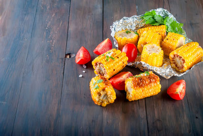 High angle view of sweetcorn and tomatoes on wooden table