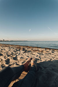 Low section of woman at beach against sky