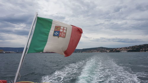Flag on boat in sea against sky