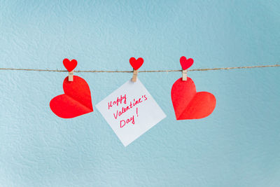 Low angle view of red heart shape on paper hanging against wall