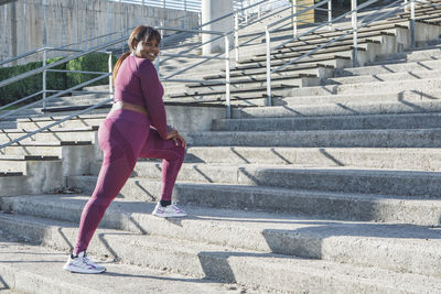 Young black woman exercising, running up steps