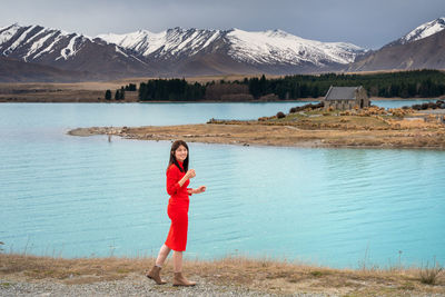 Asian female tourist pose at turquoise color lake tekapo with snowcapped mountain at the background