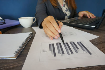 Midsection of woman using mobile phone while sitting on table